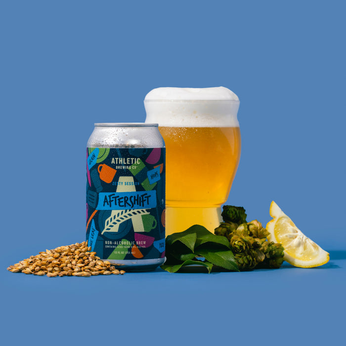 Can of non-alcoholic brew next to a glass of brew, lime, hops, and yuzu leaf