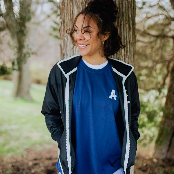 a customer wearing a a navy t-shirt with Athletic Brewing logo in a park