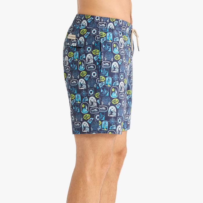 Side view of a person wearing navy blue patterned swim shorts with an allover nautical-inspired print including sailboats, shells, and ‘Run Wild’ graphics. The shorts have a straight fit, side pocket, and beige drawstring waistband.