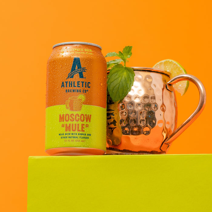 Athletic Brewing Co. "Moscow Mule" can with a copper mug on an orange background
