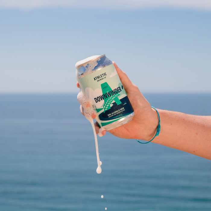 holding open can of downwinder near ocean