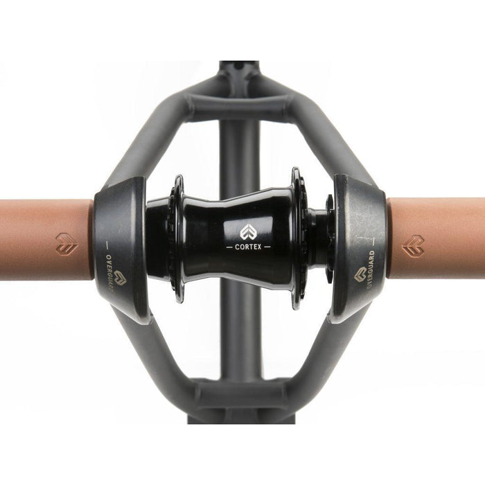 Close-up of a bicycle handlebar with brown grips, black "Cortex" stem, and the Eclat Overguard Steel Universal 14mm Hub Guard (2026), a durable chromoly hub guard for BMX bikes.