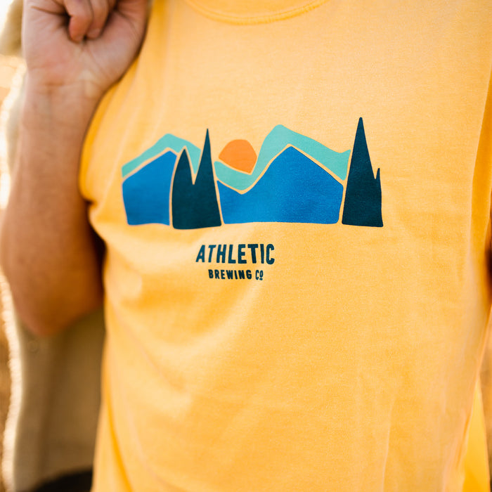 a man wearing A yellow Athletic brewing co flagship landscape t-shirt close up shot