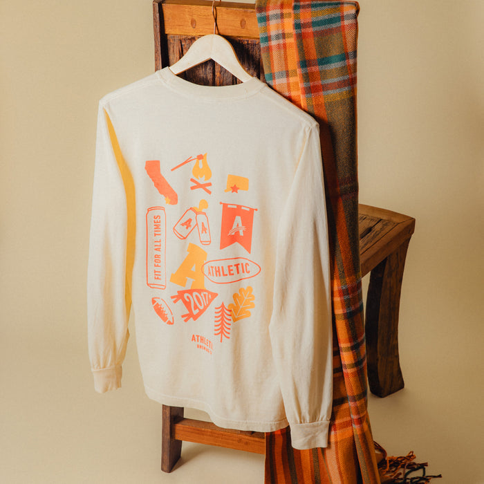 Athletic brewing co, tan long sleeve t-shirt on a hanger hanging on a chair