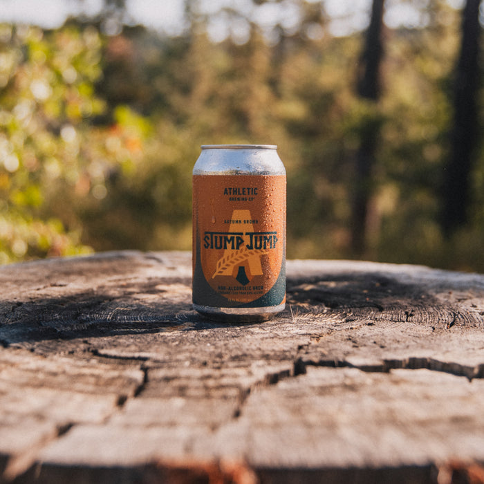 A single can of Stump Jump Non-Alcoholic Brown beer, standing upright in a forrest.